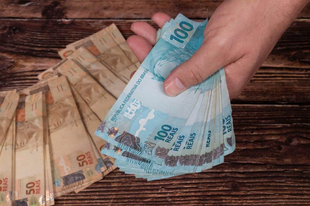 Pagamento do abono salarial em notas de 50 e 100 reais. (Fonte: Alexandre Zorek / Shutterstock).