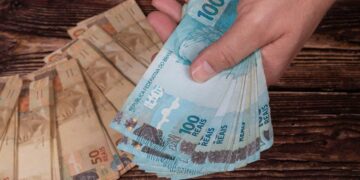 Pagamento do abono salarial em notas de 50 e 100 reais. (Fonte: Alexandre Zorek / Shutterstock).
