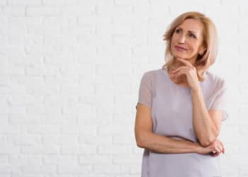 mulher de meia idade com mão sobre o queixo (Fonte: Reprodução Freepik)