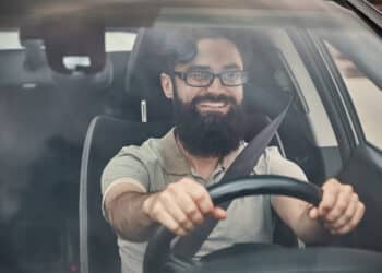 homem barbudo usando óculos conduzindo carro (Fonte: Reprodução Freepik)