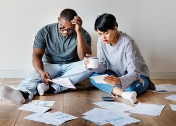 casal sentado no chão conferindo vários boletos