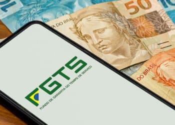 smartphone com app do fgts aberto sobre notas de 100, 50 e 20 reais (Fonte: Reprodução banQi)