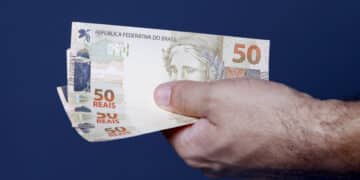 close up de mão segurando 3 notas de 50 (Fonte: Onze)