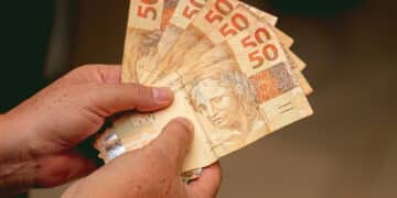 homem segurando notas de cinquenta reais