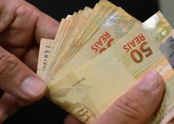 mão segurando notas de cinquenta reais