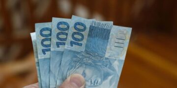 money from brazil stacked on dark wood surface - several hundred real bills