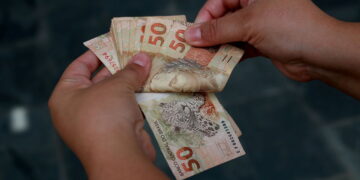 pessoa segurando notas de cinquenta reais