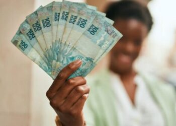 Young african american businesswoman smiling happy holding brazilian real banknotes at the city