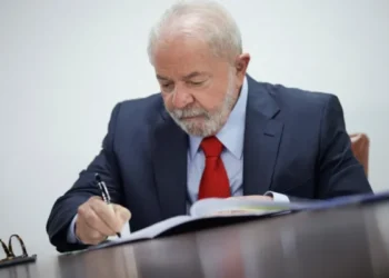 foto do presidente Lula sentado assinando documento