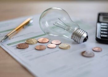 imagem de uma lampada, moedas, lapis e uma calculadora sobre a mesa